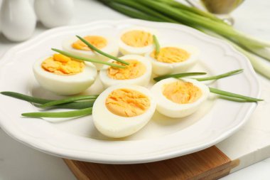 Beyaz masada yeşil soğanlı haşlanmış yumurtalar, yakın plan.