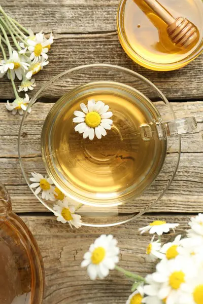 Cam fincanda nefis papatya çayı, taze çiçekler ve ahşap masada bal, düz uzanmış