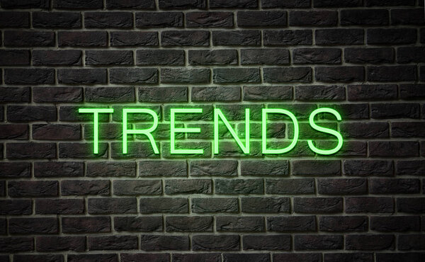 Neon sign with word Trends on black brick wall