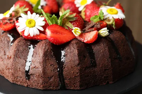 Çilekli lezzetli çikolatalı kek, papatya çiçekleri ve nane şekeri stantta, yakın plan.