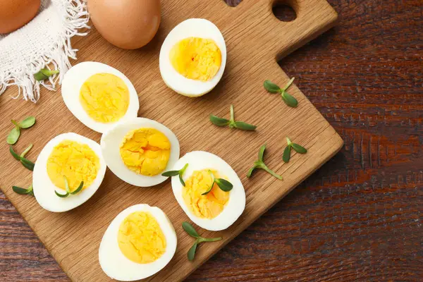 Haşlanmış yumurtaların yarısı ve ahşap masanın üstünde mikroyeşiller.