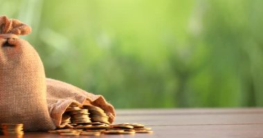 Çuval bezleri ve ahşap masaya istiflenmiş bozuk paralar bulanık arka plana karşı, sola hareket eden kamera