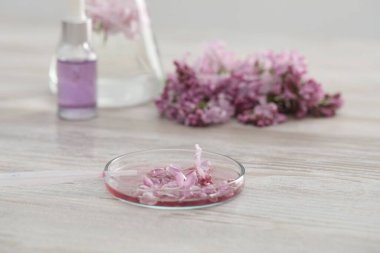 Lüks parfüm yapıyorum. Temel yağlar cam süslemede ve çiçekler beyaz ahşap masada, yakın plan.