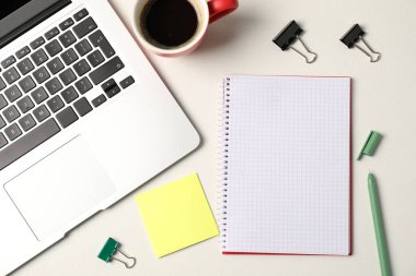 Not defteri, yapışkan not, kalem, cilt klipsleri, kahve ve dizüstü bilgisayar beyaz masada, düz yerde.