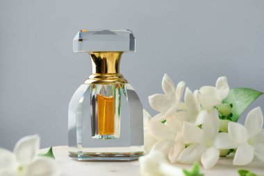 Parfüm ve yasemin çiçekleri gri arka planda, yakın plan