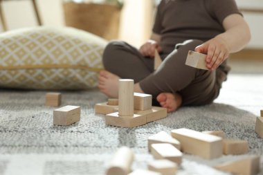 Evdeki ahşap yapı taşlarıyla oynayan sevimli küçük çocuk, yakın plan. Metin için boşluk