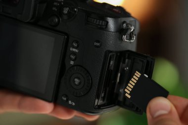 Bir adam fotoğraf makinesine SD bellek kartı yerleştiriyor.