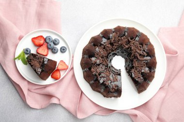 Açık gri desenli masada çilekli ve yaban mersinli lezzetli çikolatalı kek, düz konum.