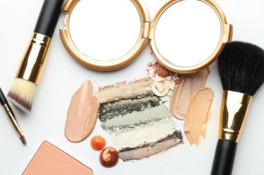 Farklı kozmetik ürünleri, makyaj fırçaları ve beyaz arka planda ayna, düz yatış