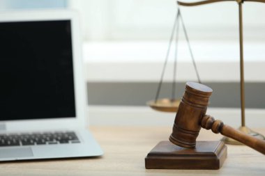 Dizüstü bilgisayar, yargıç tokmağı ve terazileri ofisteki ahşap masada, yakın plan.