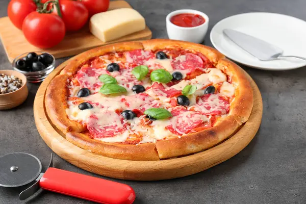 Gri masada lezzetli pizza ve malzemeler, yakın plan.