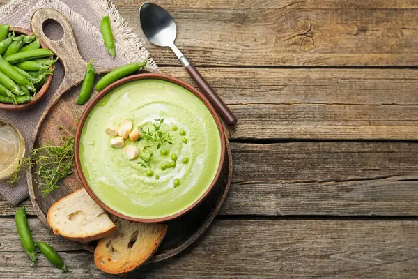 Tahta masada servis edilen kızarmış ekmek ve kekik ile bezelye kremalı leziz çorba. Metin için boşluk