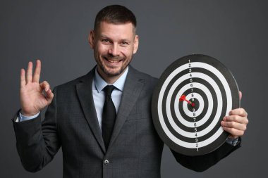 Hedef alınıyor. Ok ve dart tahtası olan adam gri arka planda iyi bir hareket gösteriyor.