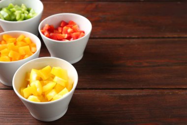 Tahta masadaki kaselerde taze dolmalık biberler, yakın plan. Metin için boşluk