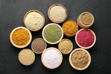 Koyu dokulu masada, düz bir zeminde, kaselerdeki farklı süper yiyecek tozları.