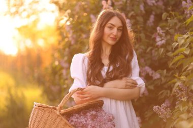 Güzel bir kadın ve açık havada bir sepet leylak çiçeği.