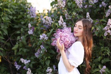 Leylak çiçeklerinin arasında güzel bir kadın ve açık havada bırakır