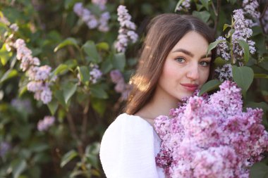 Leylak çiçeklerinin arasında güzel bir kadın ve açık havada bırakır