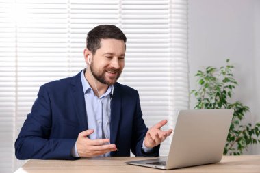 Gülümseyen çevrimiçi hoparlör masadaki dizüstü bilgisayarla internetten yayın yapıyor.