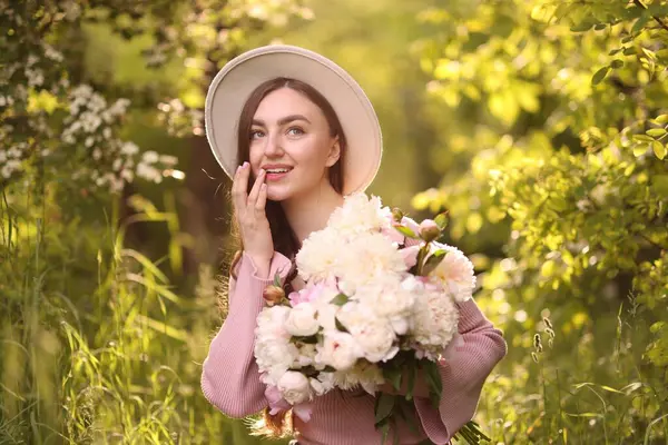Parkta şakayık demeti olan güzel bir kadın.