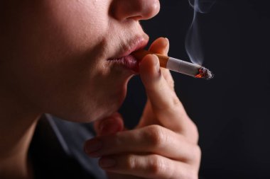 Siyah arka planda sigara içen kadın, yakın plan.