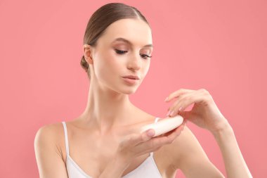 Pembe arka planda sabun çubuğu olan güzel bir kadın.