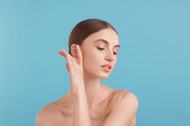 Açık mavi arka planda büyüleyici genç bir kadının portresi.