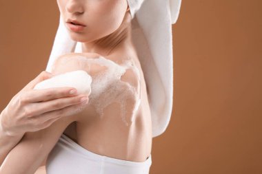 Kahverengi arka planda sabunlu kadın cesedi yıkıyor, yakın plan. Metin için boşluk