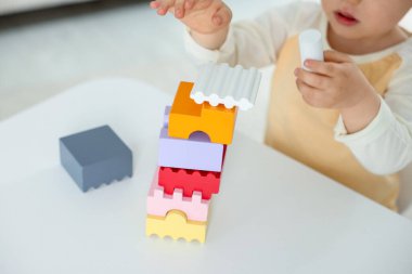 Beyaz masadaki tuğlalarla oynayan sevimli küçük çocuk, yakın plan.