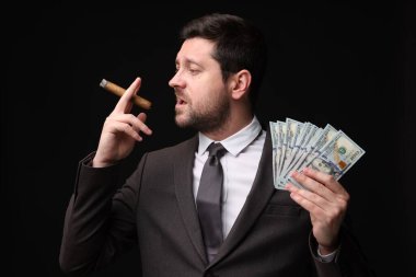Dolar banknotları olan açgözlü bankacı siyah arka planda puro içiyor.