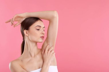 Pembe arkaplandaki epilasyondan sonra pürüzsüz cilt gösteren genç kadın, metin için boşluk