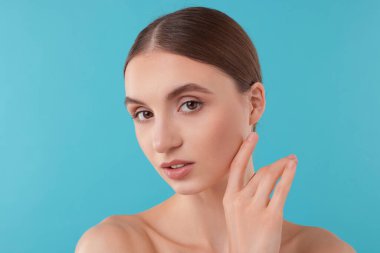 Açık mavi arka planda büyüleyici genç bir kadının portresi.