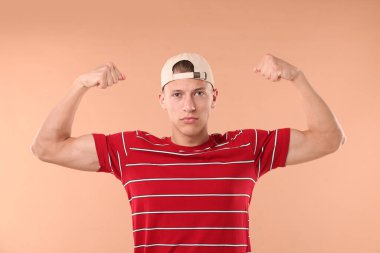 Beyzbol şapkalı genç adam bej arka planda.