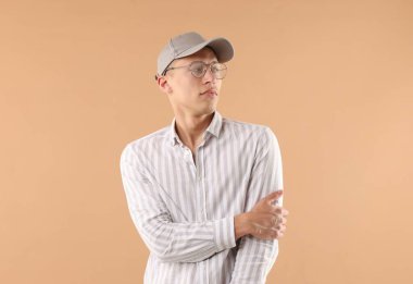 Beyzbol şapkalı genç adam bej arka planda.