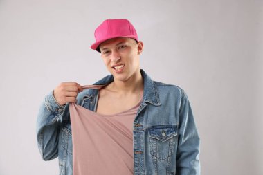 Açık gri arka planda şık bir beyzbol şapkası takan genç adam.