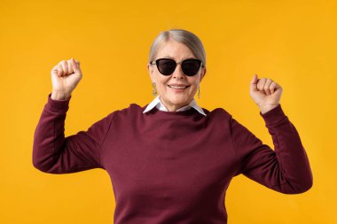 Turuncu arka planda şık giyinmiş mutlu bir son sınıf kadını.