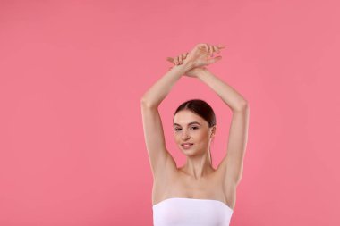 Pembe arka plandaki epilasyondan sonra pürüzsüz bir ten gösteren genç kadın.