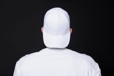 Siyah arka planda şık bir beyaz beysbol şapkası giyen genç adam.