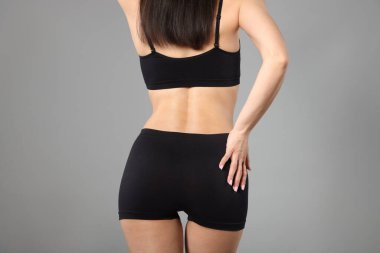 Gri arka planda mükemmel ince vücutlu kadın, yakın plan.