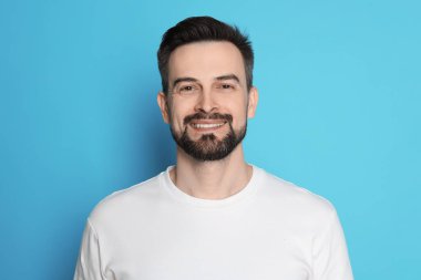 Açık mavi arka planda tıraş olmadan önce gülümseyen adam