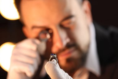 Kapalı alanda lüks yüzük değerlendirmesi yapan, seçici odaklı bir eksper.