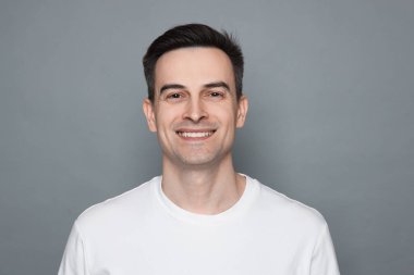 Gri arka planda tıraş olduktan sonra gülümseyen adam