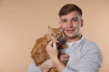 Bej arka planda sevimli kızıl kedisi olan adam.