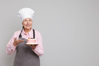 Açık gri arka planda pasta gösteren profesyonel bir şekerci. Metin için boşluk