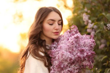 Güzel bir kadın ve açık havada bir demet leylak çiçeği, yakın plan.