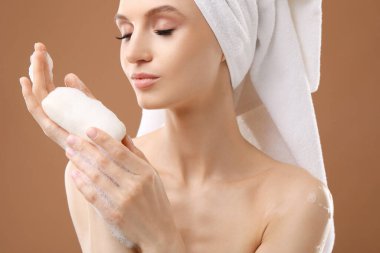 Kahverengi arka planda sabun çubuğu olan güzel kadın, yakın plan.