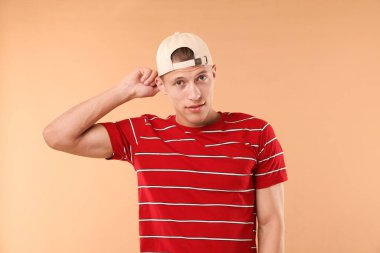 Beyzbol şapkalı genç adam bej arka planda.