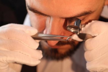 Kapalı alanda lüks mücevher değerlendirmesi yapan loupe 'a değer biçen bir eksper.