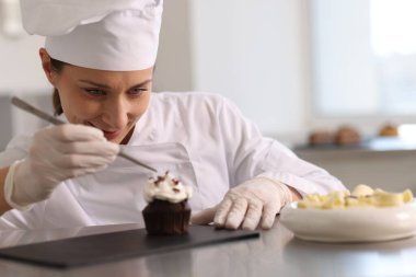 Şekerci, mutfakta çikolata parçalarıyla kek süslüyor.