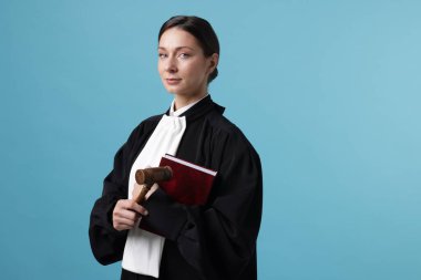 Açık mavi arkaplan üzerine kitap ve çekiçle yargıç